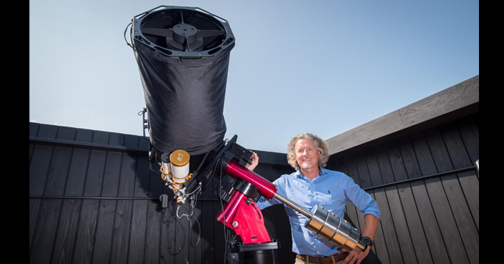 Astronomer Gary Fildes standing next to large telescope